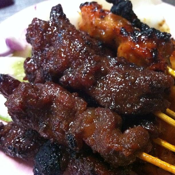 Kepingan sate daging dan ayam yang dibakar disajikan bersama kuah kacang.