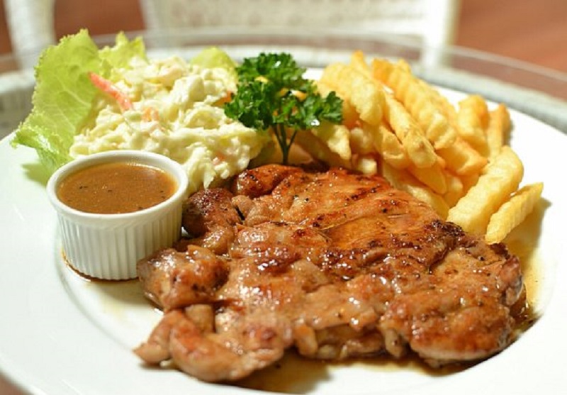 Hidangan chicken chop dengan sos lada hitam, coleslaw dan french fries.