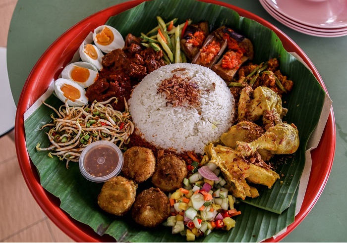 Gambar nasi ambeng, hidangan nasi putih dengan pelbagai lauk pauk mengelilinginya di atas dulang.