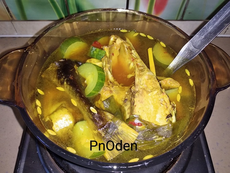 Asam rebus dengan kuah yang banyak dan nenas dimasak dalam periuk.