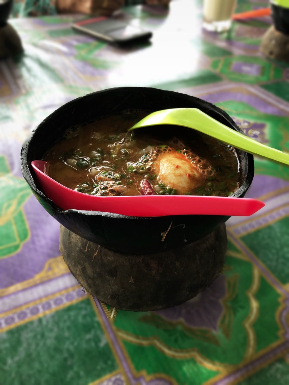 Semangkuk laksa penang yang pekat dengan hidangan sambal dan ulam.