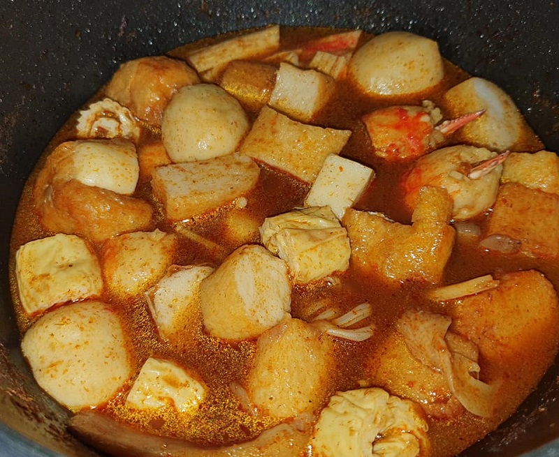 Mangkuk kuah steamboat masam manis pedas dengan pelbagai bahan steamboat dan cendawan.