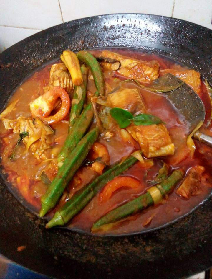 Gambaran hidangan ikan pari bakar yang dibalut dengan daun pisang dan berselerak sambal cili yang menggugah selera.