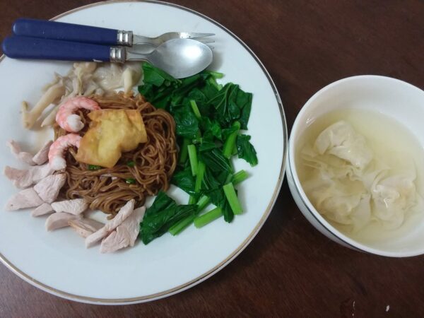 Wantan mee disajikan dengan sayur sawi dan hiasan.