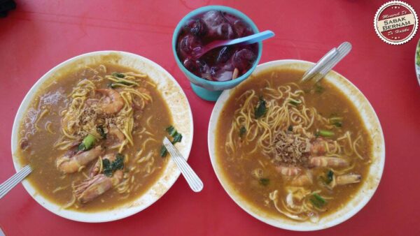 Mee udang dengan kuah kemerahan dan udang besar.