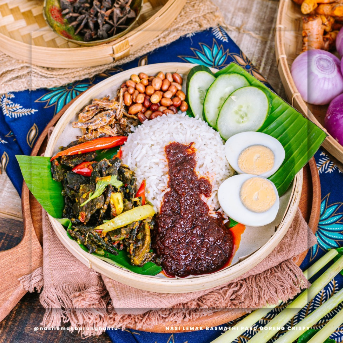 Nasi lemak dengan lauk ayam berempah dihidang atas daun pisang.