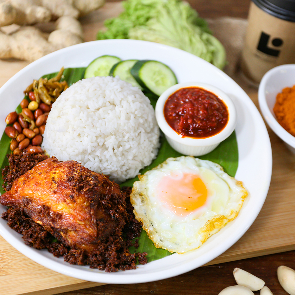 Pelbagai hidangan nasi lemak dengan lauk ayam goreng dan sambal di atas daun pisang